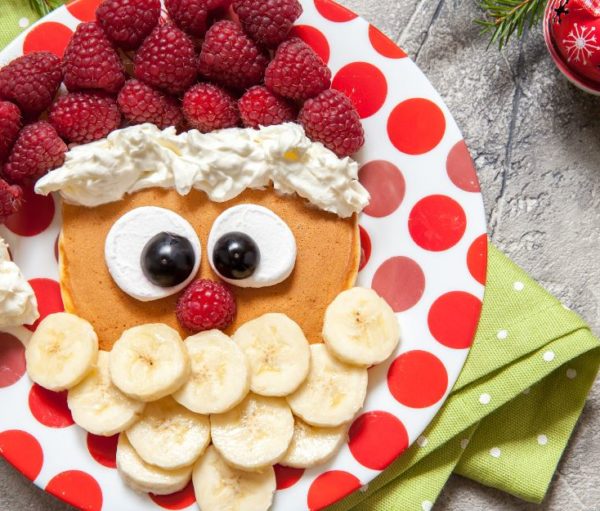 pancakes decorated to look like Santa on holiday-decorated table